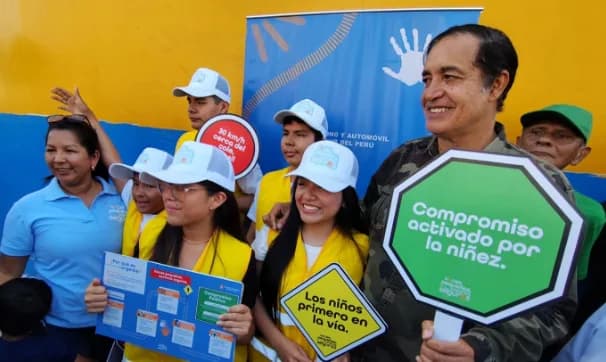 Alex Gonzáles con niñas y niños del programa Voces Pequeñas sosteniendo carteles de seguridad vial